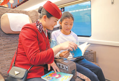 從北京開往南昌的列車上，乘務(wù)人員與小旅客一起閱讀。王夢婧子攝